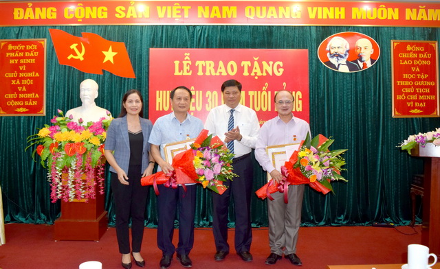 Đồng chí Lương Văn Đoàn - Bí thư Đảng uỷ - trao quyết định, Huy hiệu 30 năm tuổi Đảng và tặng hoa chúc mừng đồng chí Trần Trọng Thành và đồng chí Nguyễn Văn Thơi.